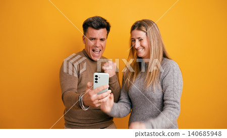 Couple celebrating success winning online using smartphone Couple celebrating success winning online using smartphone 140685948