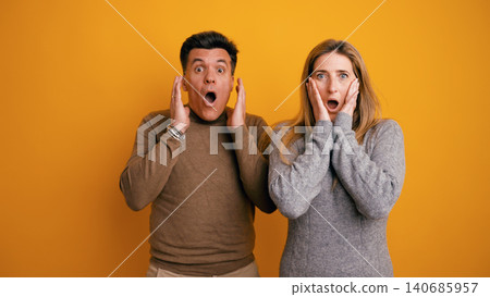 Couple expressing shock and surprise on yellow background 140685957