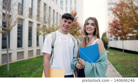 Smiling students holding folders standing on campus Smiling students holding folders standing on campus 140686246