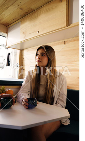 Young woman drinking coffee in camper van Young woman drinking coffee in camper van 140686430