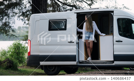 Woman enjoying van life camping by a lake Woman enjoying van life camping by a lake 140686437