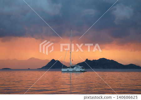 Red sky and sailing boat at sunset before the storm. Red sky and sailing boat at sunset before the storm. 140686625