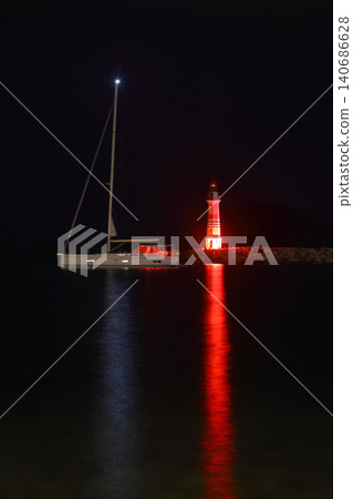 lighthouse and sailboat at dusk. With reflections in the water. lighthouse and sailboat at dusk. With reflections in the water. 140686628