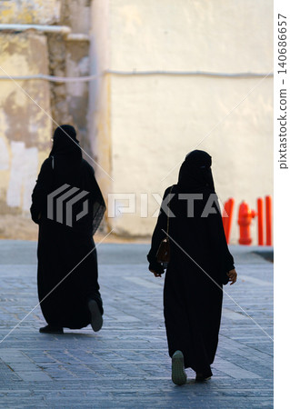 Jeddah, Saudi Arabia - Mar 08 2023, two Arab woman dressing in black burqa, paranja, walking down the street in old town of Jeddah, Saudi Arabia Jeddah, Saudi Arabia - Mar 08 2023, two Arab woman dressing in black burqa, paranja, walking down the street in old town of Jeddah, Saudi Arabia 140686657