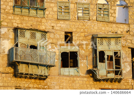 Jeddah, Saudi Arabia, panoramic view of the wall of a house with broken, dilapitated mashrabiya wooden balconies in the old town of Jeddah, at daytime Jeddah, Saudi Arabia, panoramic view of the wall of a house with broken, dilapitated mashrabiya wooden balconies in the old town of Jeddah, at daytime 140686664