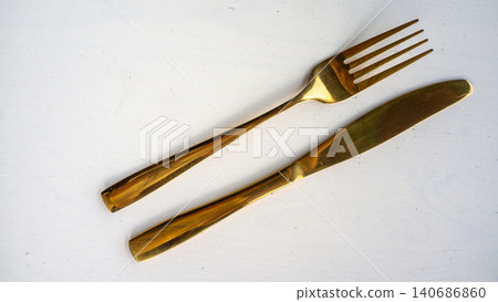 Golden cutlery set with fork and knife arranged on clean white background Golden cutlery set with fork and knife arranged on clean white background 140686860