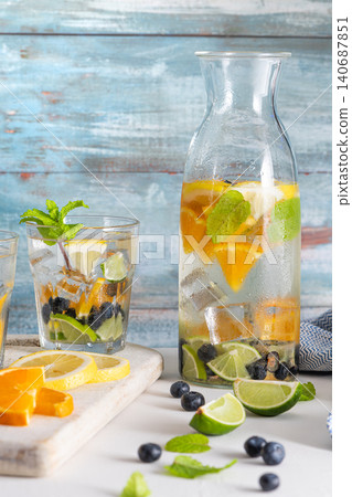 Summer healthy cocktails of citrus infused waters, lemonades or mojitos, with lime lemon orange blueberries and mint, diet detox beverages, in glasses on light background Summer healthy cocktails of citrus infused waters, lemonades or mojitos, with lime lemon orange blueberries and mint, diet detox beverages, in glasses on light background 140687851