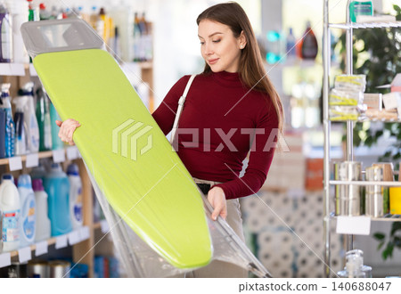 Young woman chooses ironing board in store Young woman chooses ironing board in store 140688047