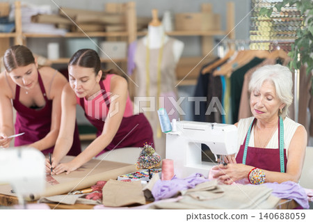 Mature head of cloth manufacturing sewing, two assistant drawing paper dress pattern by curves Mature head of cloth manufacturing sewing, two assistant drawing paper dress pattern by curves 140688059
