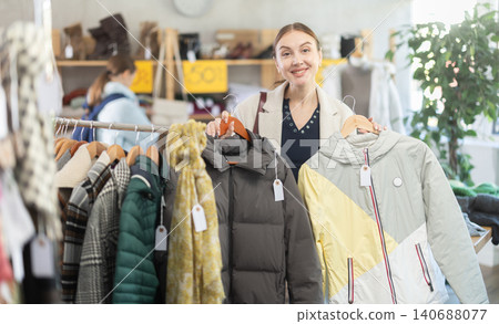 Adult woman chooses down jacket in clothing store Adult woman chooses down jacket in clothing store 140688077
