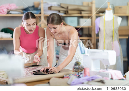 Two female designers drawing sketches in a workshop 140688080