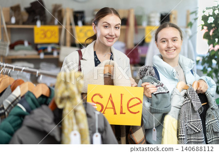 Happy mom and teenage daughter holding sale banner in clothing store 140688112