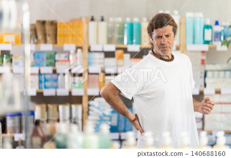 man holding his back in a pharmacy 140688160