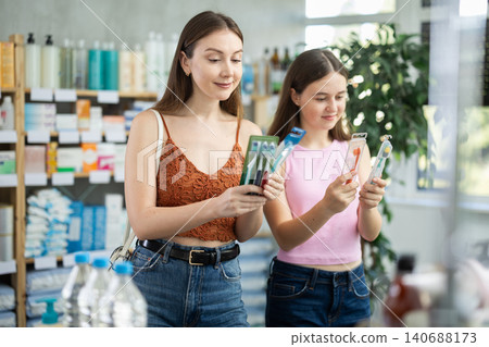 Woman with daughter choosing toothbrush in pharmacy 140688173