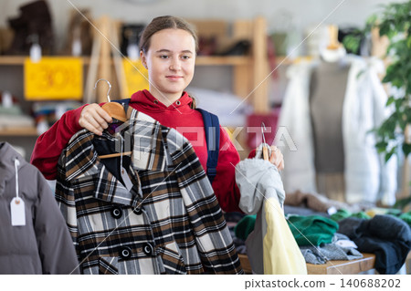European teen customer examine and choose new coat for cold season in modern store. Black Friday sale of winter clothing collection European teen customer examine and choose new coat for cold season in modern store. Black Friday sale of winter clothing collection 140688202