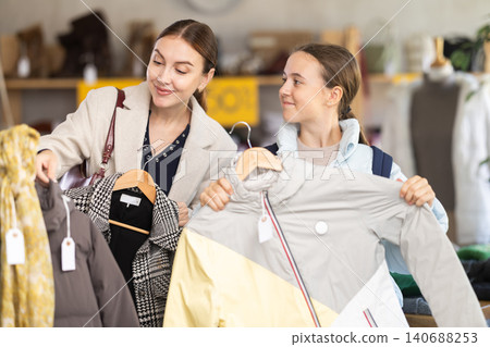 Mom and teenage daughter choosing down jacket in clothing store Mom and teenage daughter choosing down jacket in clothing store 140688253