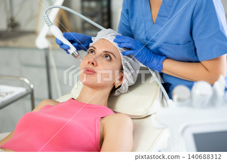 Adult woman cosmetologist doing cleansing procedure to young woman Adult woman cosmetologist doing cleansing procedure to young woman 140688312