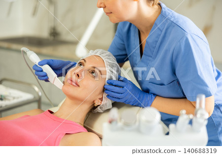 Adult woman cosmetologist doing exfoliation procedure to young woman Adult woman cosmetologist doing exfoliation procedure to young woman 140688319