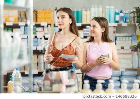 woman and her daughter are standing in a pharmacy with a medical prescription woman and her daughter are standing in a pharmacy with a medical prescription 140688326