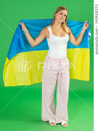 Teenage girl holding Ukrainian flag in front of green screen Teenage girl holding Ukrainian flag in front of green screen 140688353