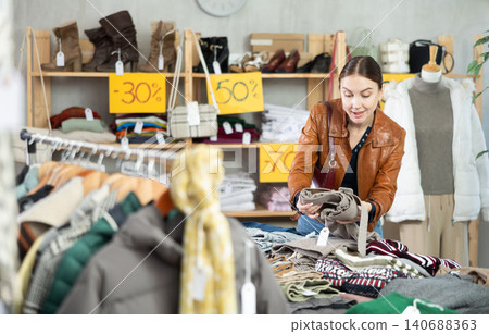 woman stands near the counter and chooses her pants woman stands near the counter and chooses her pants 140688363