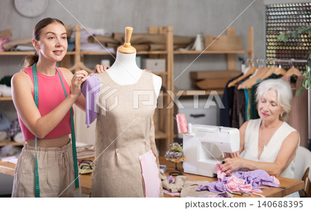 Senior woman tailor busy with sewing machine, female employee work with mannequin Senior woman tailor busy with sewing machine, female employee work with mannequin 140688395