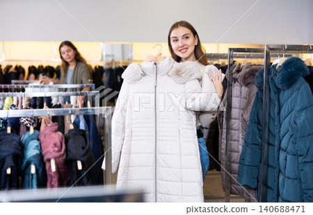 Young woman choosing insulated coat in store Young woman choosing insulated coat in store 140688471