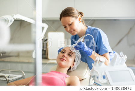 Adult woman cosmetologist doing whitening procedure to young woman Adult woman cosmetologist doing whitening procedure to young woman 140688472