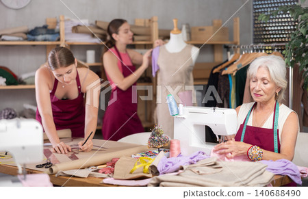 Seamstress staff sew, assistant work with mannequin, designer draw dress pattern on paper Seamstress staff sew, assistant work with mannequin, designer draw dress pattern on paper 140688490