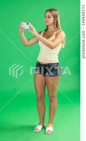 Teenage girl taking photo in front of green screen Teenage girl taking photo in front of green screen 140688531