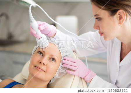 Professional beautician makes cryotherapy for rejuvenation woman face, anti aging procedure and shrink pores and repair damaged skin in salon Professional beautician makes cryotherapy for rejuvenation woman face, anti aging procedure and shrink pores and repair damaged skin in salon 140688551