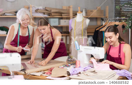 Dressmakers draw sketches of clothes and work on a sewing machine in the workshop 140688582