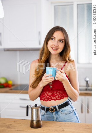 Woman drinking coffee at kitchen in morning 140688583