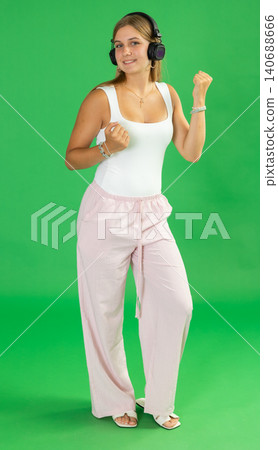 Teenage girl listening to music and dancing in front of green screen Teenage girl listening to music and dancing in front of green screen 140688666