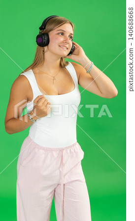 Teenage girl listening to music and dancing in front of green screen Teenage girl listening to music and dancing in front of green screen 140688668