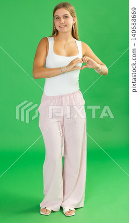 Teenage girl making heart gesture with hands in front of green screen Teenage girl making heart gesture with hands in front of green screen 140688669