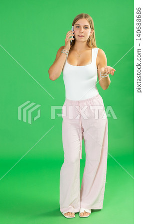 Teenage girl talking on mobile phone in front of green screen Teenage girl talking on mobile phone in front of green screen 140688686
