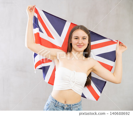 Girl holds unfolded canvas flag of Great Britain in front of her 140688692