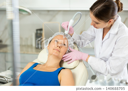 Professional female cosmetologist doing hydrafacial procedure in cosmetology clinic. Doctor use hydrogen and oxygen small bubbles for deeply clear skin. Rejuvenation and hydratation 140688705