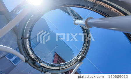 Low angle abstract view of a spiral outdoor slide structure against blue sky in Japan. Low angle abstract view of a spiral outdoor slide structure against blue sky in Japan. 140689013