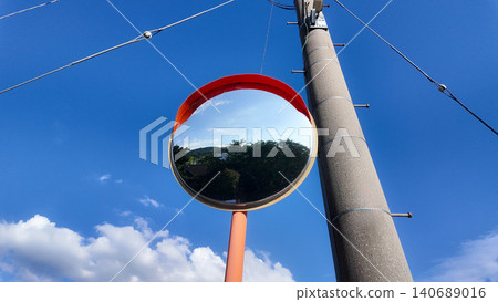 Low angle shot of a round traffic convex mirror next to a utility pole against blue sky. Low angle shot of a round traffic convex mirror next to a utility pole against blue sky. 140689016