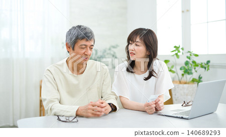 A couple in their 60s looking at a computer and cards in the living room A couple in their 60s looking at a computer and cards in the living room 140689293