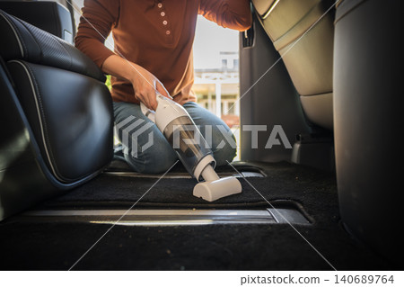 close up hand of woman using portable handheld vacuum cleaner to cleaning the floor mat of her luxury car close up hand of woman using portable handheld vacuum cleaner to cleaning the floor mat of her luxury car 140689764