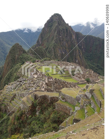 A panoramic view of the mystical Machu Picchu ruins shrouded in mist, and Mount Huayna Picchu (Peru). A panoramic view of the mystical Machu Picchu ruins shrouded in mist, and Mount Huayna Picchu (Peru). 140689998