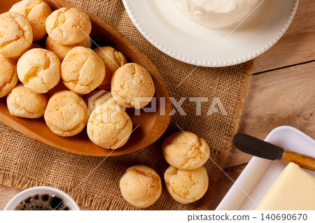 Homemade Brazilian cheese bread served on a wooden platter, accompanied by fresh Minas cheese, butter, and black coffee Homemade Brazilian cheese bread served on a wooden platter, accompanied by fresh Minas cheese, butter, and black coffee 140690670