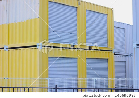 Two stacks of yellow, shuttered rental storage containers in an outdoor area. Two stacks of yellow, shuttered rental storage containers in an outdoor area. 140690985