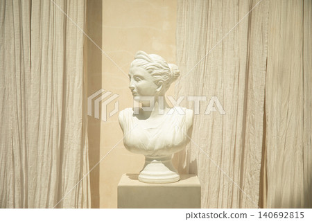 Marble bust of a woman placed on a pedestal surrounded by fabric Marble bust of a woman placed on a pedestal surrounded by fabric 140692815