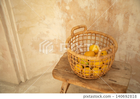 Fresh lemons in a woven basket on a wooden stool Fresh lemons in a woven basket on a wooden stool 140692818