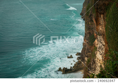 Cliffs overlook ocean waves with rocks and greenery at Bali Cliffs overlook ocean waves with rocks and greenery at Bali 140692847