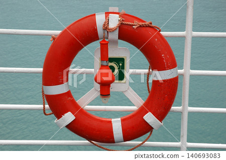 Orange lifebuoy with safety light on a cruise ship railing 140693083